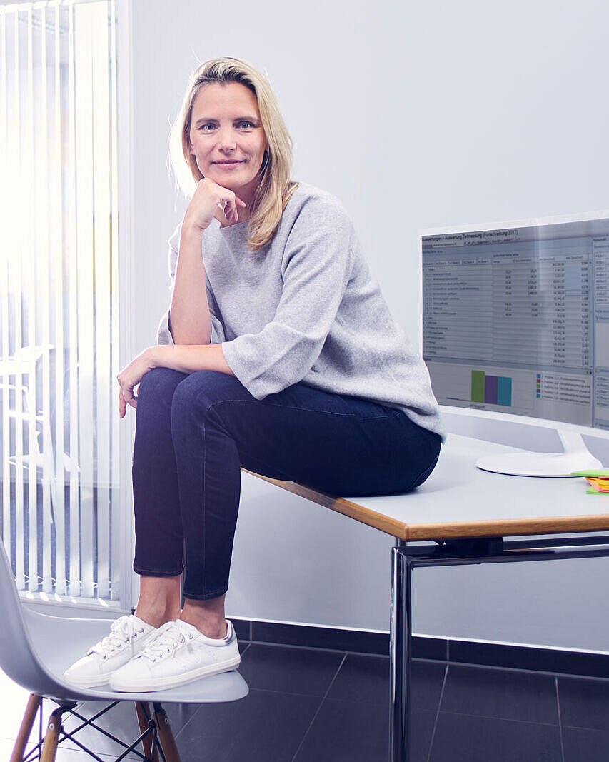 Effizient Arbeiten und Organisieren mit ibo Beraterin und Weiterbildungsleiterin von ibo sitzt im Unternehmen auf einem Schreibtisch