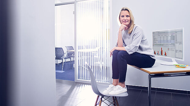 Effizient Arbeiten und Organisieren mit ibo Beraterin und Weiterbildungsleiterin von ibo sitzt im Unternehmen auf einem Schreibtisch