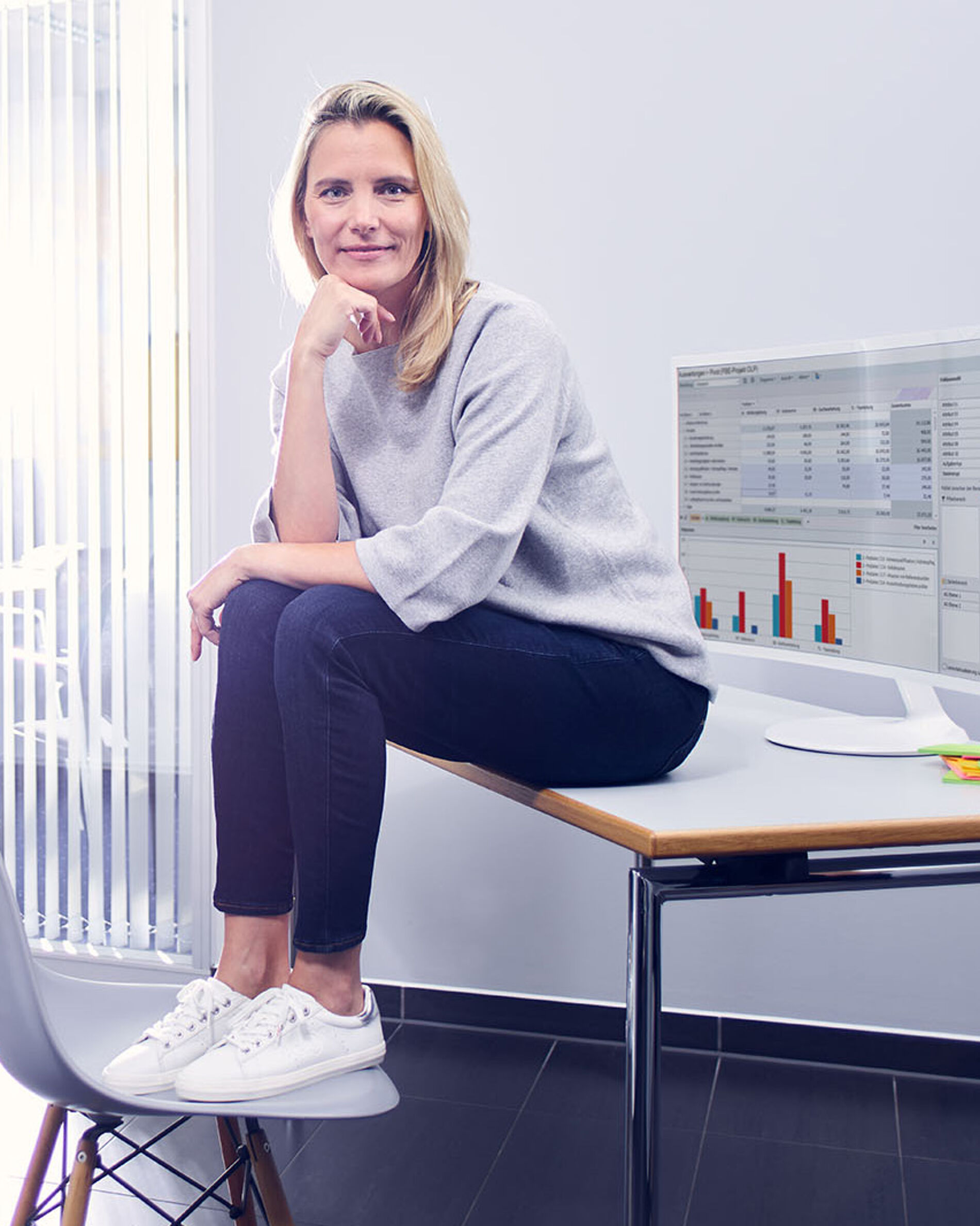 Effizient Arbeiten und Organisieren mit ibo Beraterin und Weiterbildungsleiterin von ibo sitzt im Unternehmen auf einem Schreibtisch
