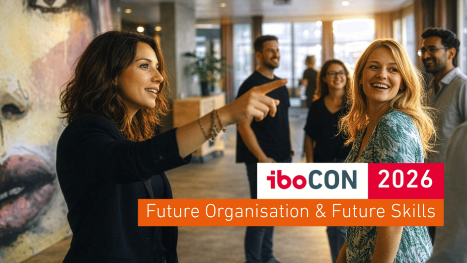 Leitmotiv der iboCON 2026 - Gruppe von Menschen in einem modernen Raum; eine Person zeigt erklärend nach vorne, eine andere lacht zur Gruppe. Zwei Gesichter im Vordergrund sind scharf, die übrigen Personen und die Architektur im Hintergrund leicht unscharf. Warmes Gegenlicht durch große Fenster erzeugt eine inspirierende, dynamische Aufbruchsstimmung. (Bild wurde mit KI-Unterstützung erstellt)