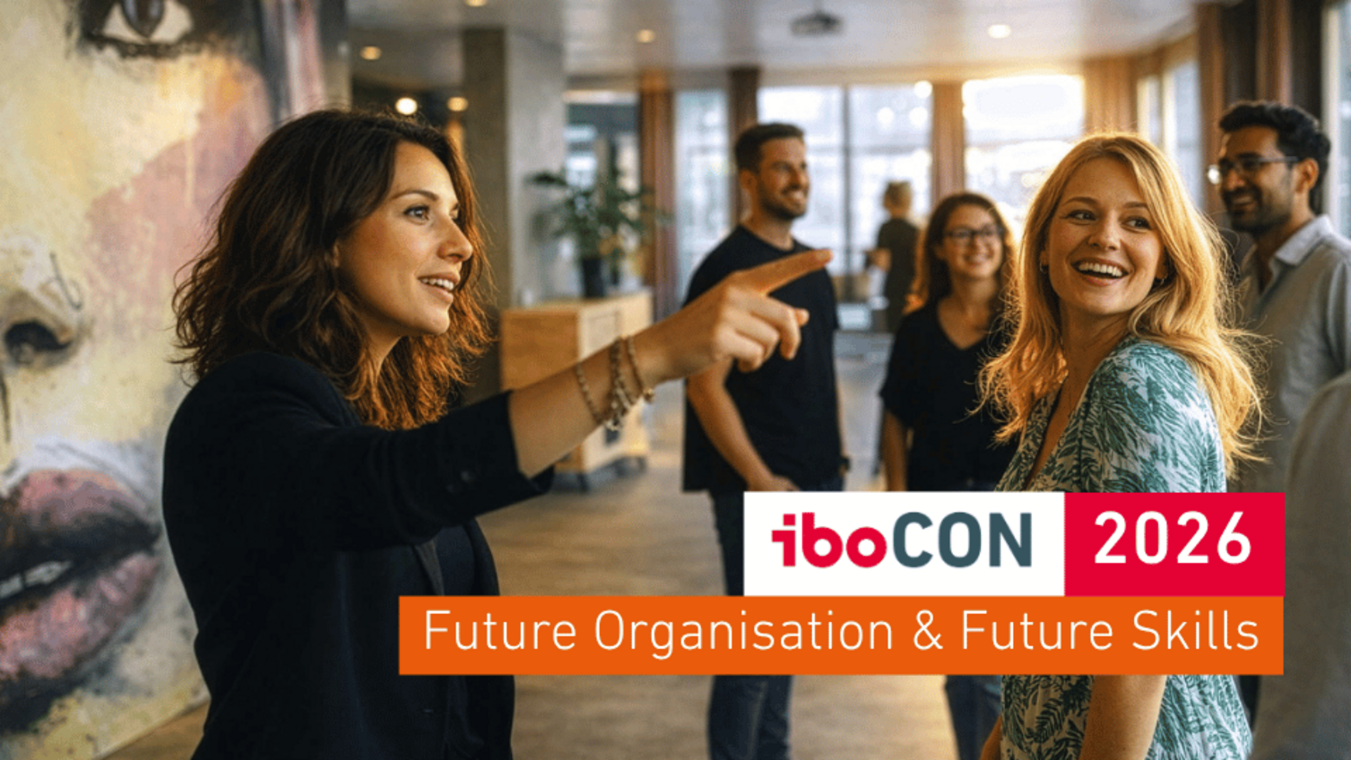 Leitmotiv der iboCON 2026 - Gruppe von Menschen in einem modernen Raum; eine Person zeigt erklärend nach vorne, eine andere lacht zur Gruppe. Zwei Gesichter im Vordergrund sind scharf, die übrigen Personen und die Architektur im Hintergrund leicht unscharf. Warmes Gegenlicht durch große Fenster erzeugt eine inspirierende, dynamische Aufbruchsstimmung.
