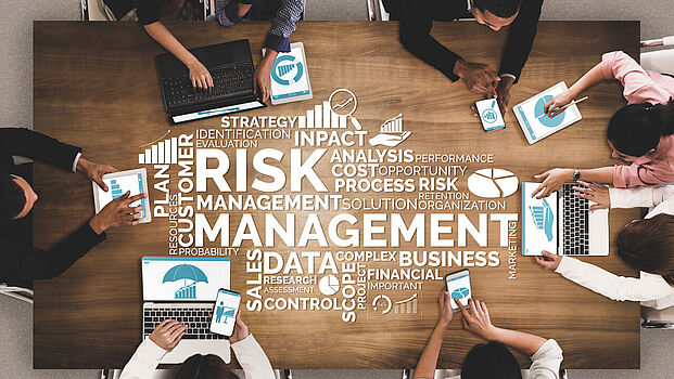 Blick auf Tisch mit Mitarbeitern und verschiedenen Risiken