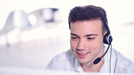 Support von ibo Support Mitarbeiter von ibo mit Headset am Computer