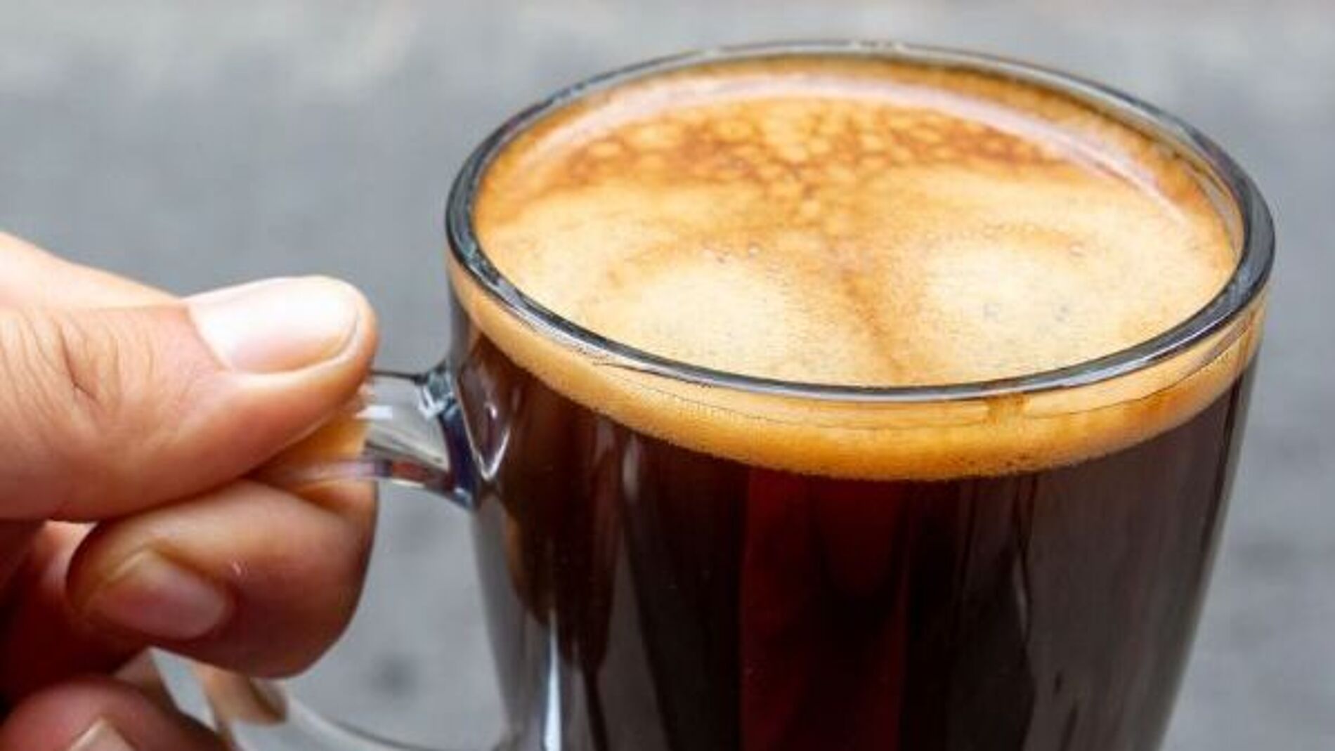 Kaffee in Glastasse in der Hand
